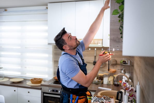 Male contractor measuring a kitchen cabinet