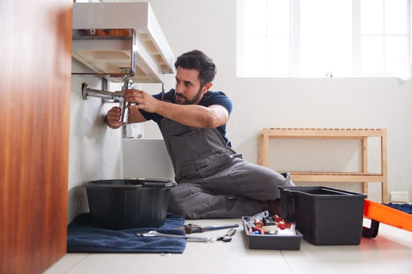 Male landlord fixes bathroom plumbing in rental property