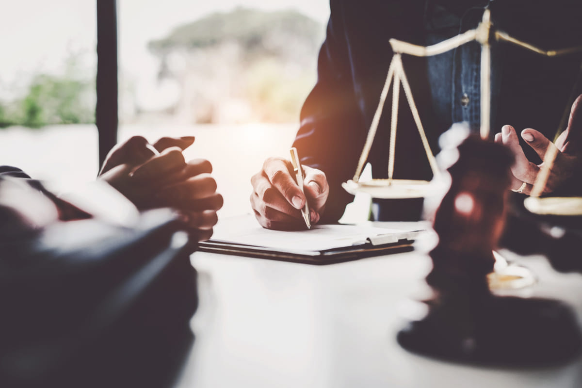 A lawyer writing on a document next to a scale