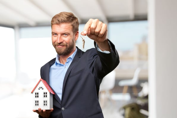 A man holding a model house and keys