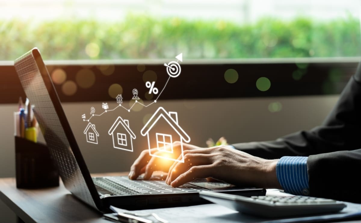 A person working on a laptop showing a graph and houses