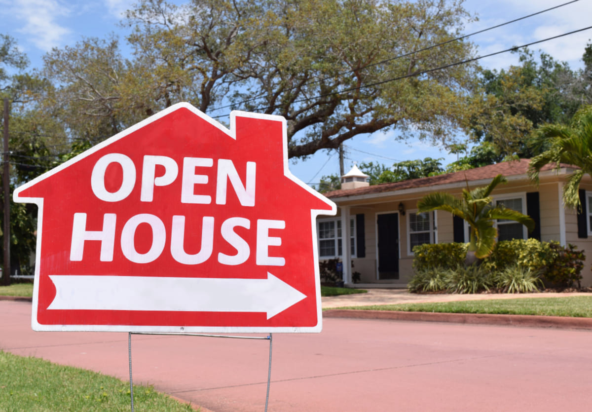 A red sign that says open house pointing to a house