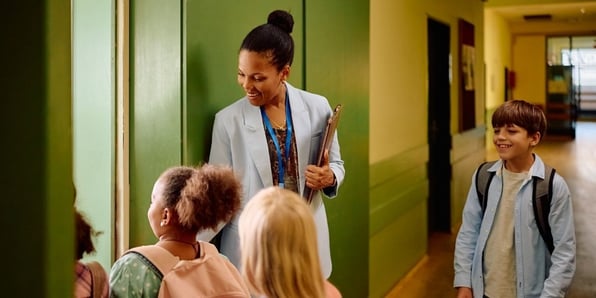 A teacher greeting students as they come into class.