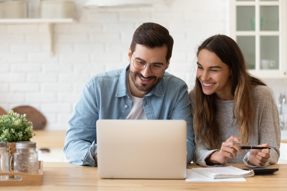 Happy couple looking at a laptop, Rhino security deposit insurance benefits for tenants concept