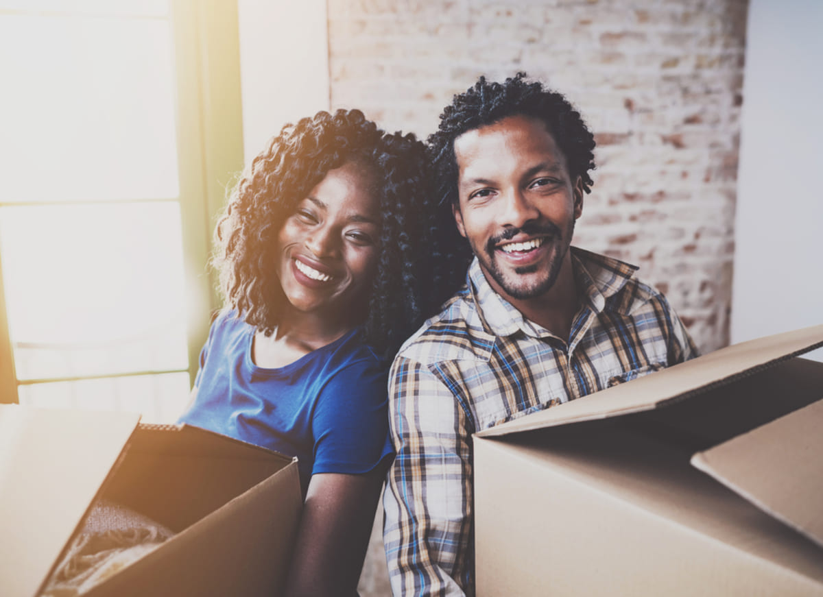 Happy couple with moving boxes, keeping tenants longer with rental management companies