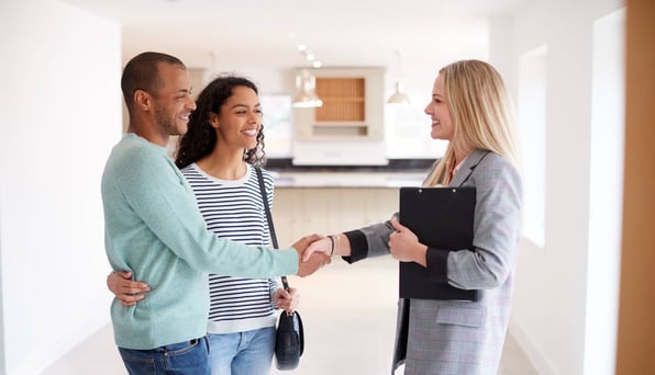 Female property manager shakes hands with male and female tenants