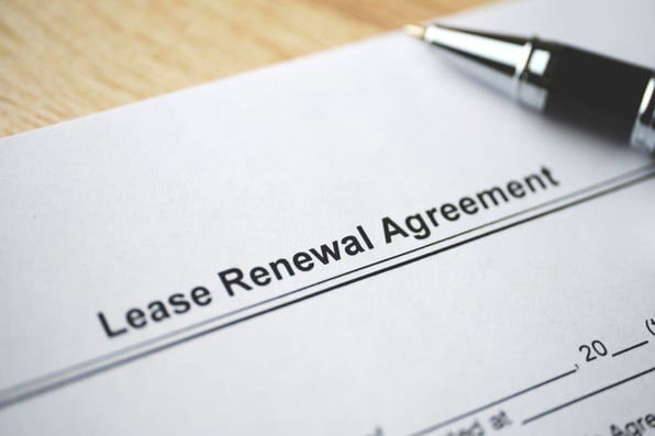 Paper that says lease renewal agreement next to a pen
