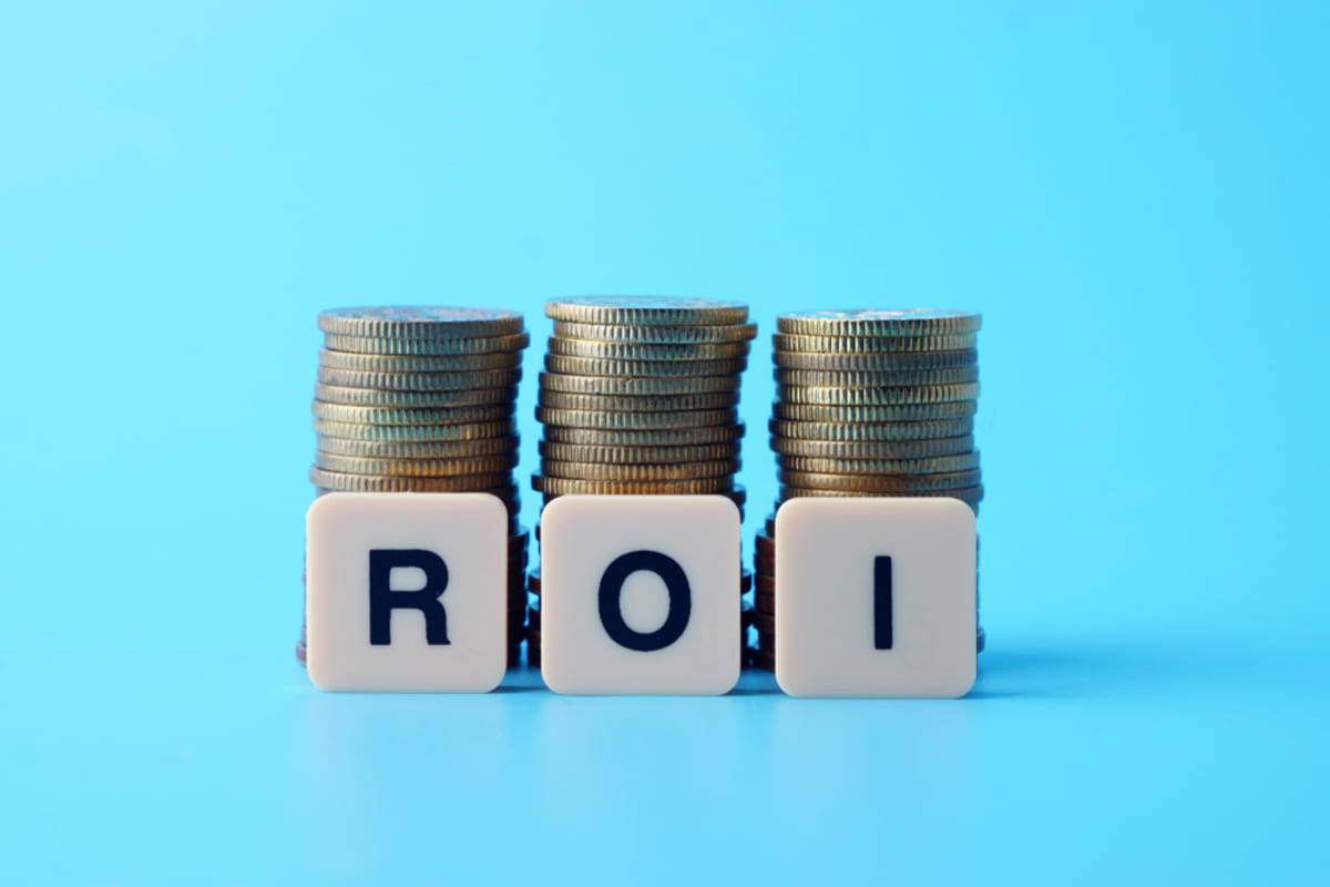 Plastic letters that spell out ROI in front of stacks of coins