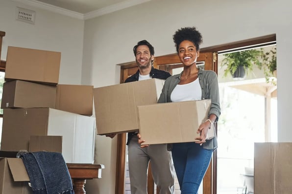 Married couple carrying moving boxes into Hampton Roads rental home
