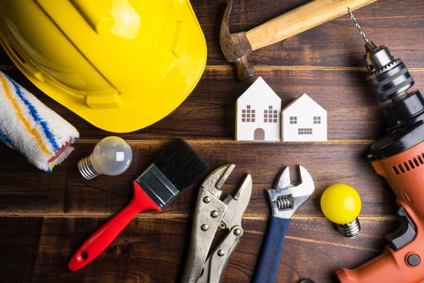 Small wooden houses on a table with maintenance tools around them