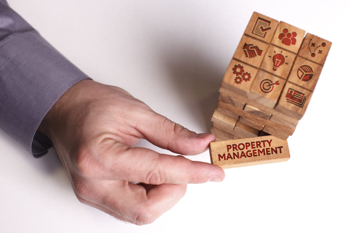 Someone holding a wood block labeled property management
