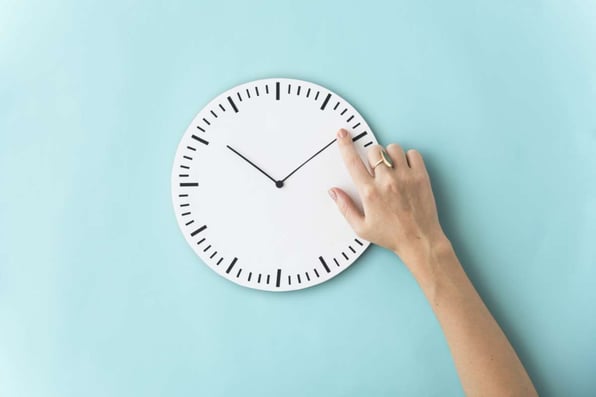 A hand moves hands on a clock for the right time to hire a Norfolk property management company