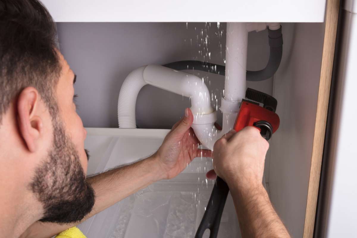 Close-up Of A Man Repairing Sink Pipe Leakage With Adjustable Wrench