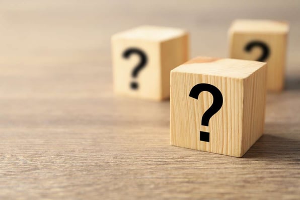 Cube with question mark on wooden background