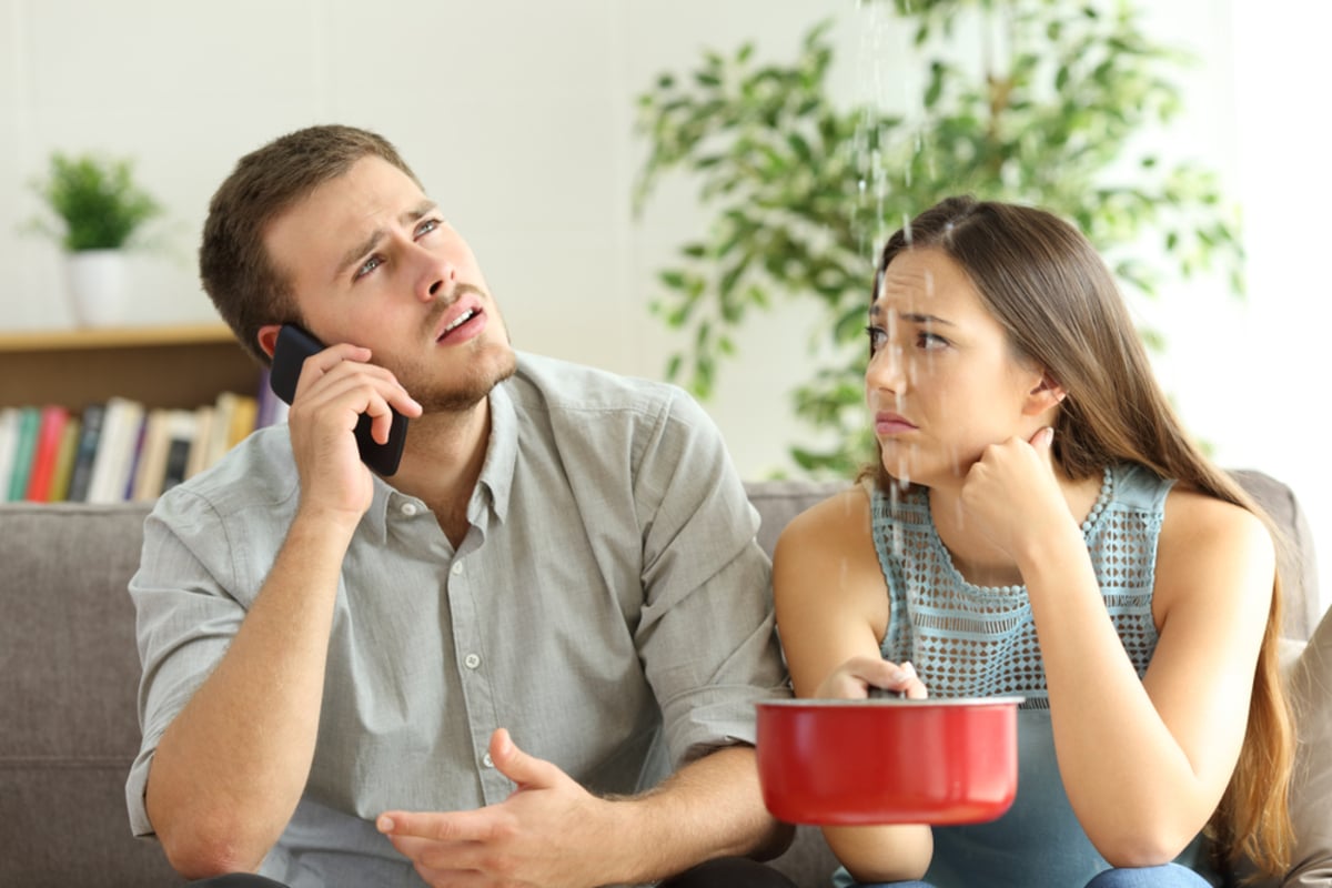 Desperate couple calling to insurance worried about home leaks in the living room