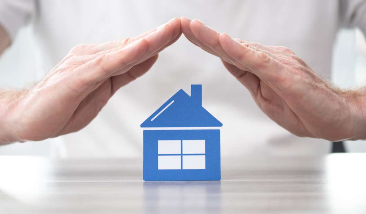 Hands over a blue house model, rental management companies protection concept