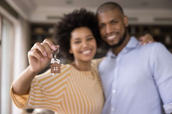 Happy couple showing keys, eviction prevention concept. 