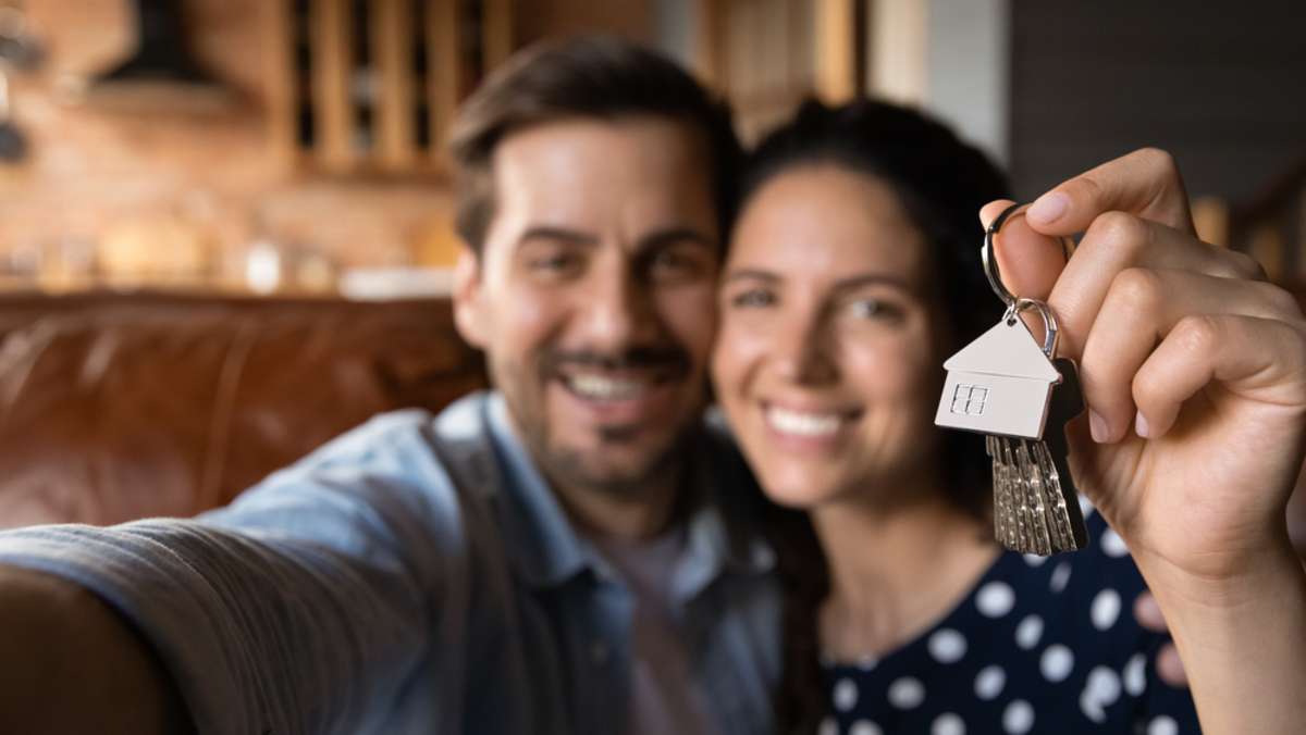 Happy husband and wife showing key at camera, move-in checklist concept. 