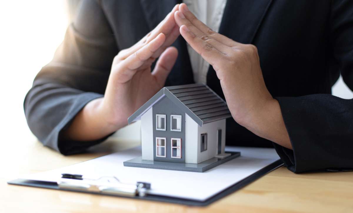 Close-up of hands over a model home, Virginia Beach property management protects rentals concept. 