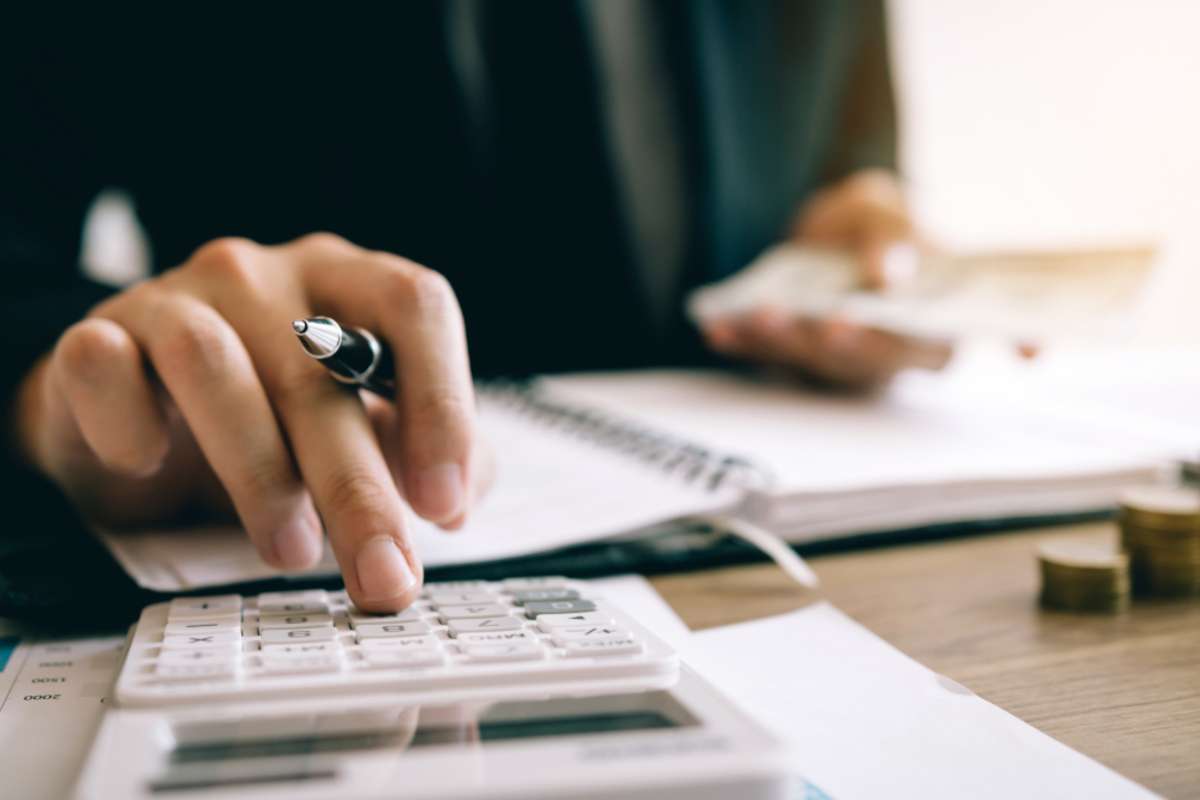 Investors are calculating on calculator investment costs and holding cash notes in hand