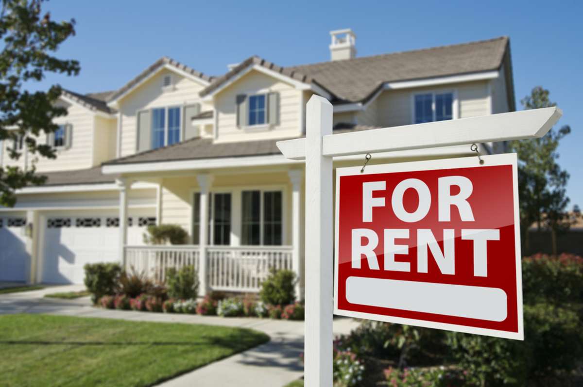 Left Facing Red For Rent Real Estate Sign in Front of Beautiful House