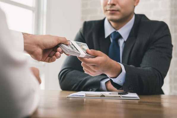 Man handing cash as rental payment to real estate management companies