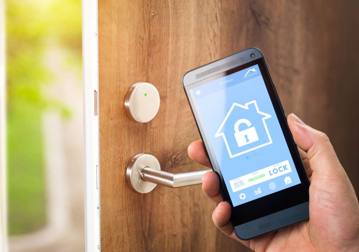 Man uses his smartphone with smarthome security app to unlock the door of his house