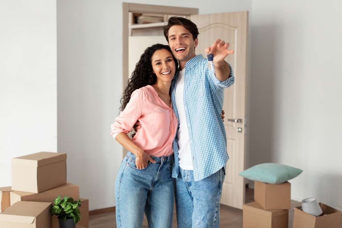 A couple with house keys in a new rental home, property management companies set the ideal rate concept. 