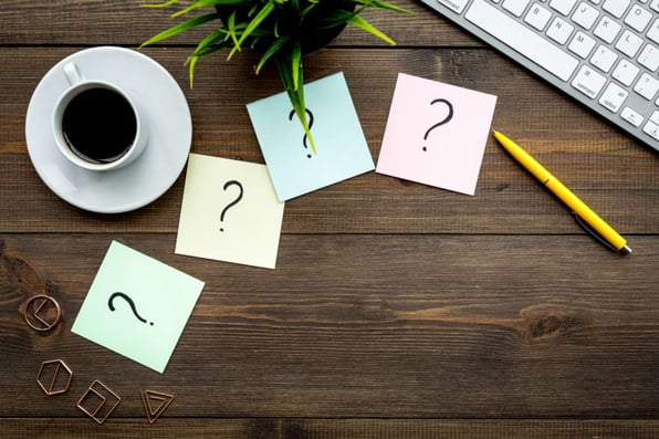 Question mark on sticky notes on office desk on dark wooden background top view copy space