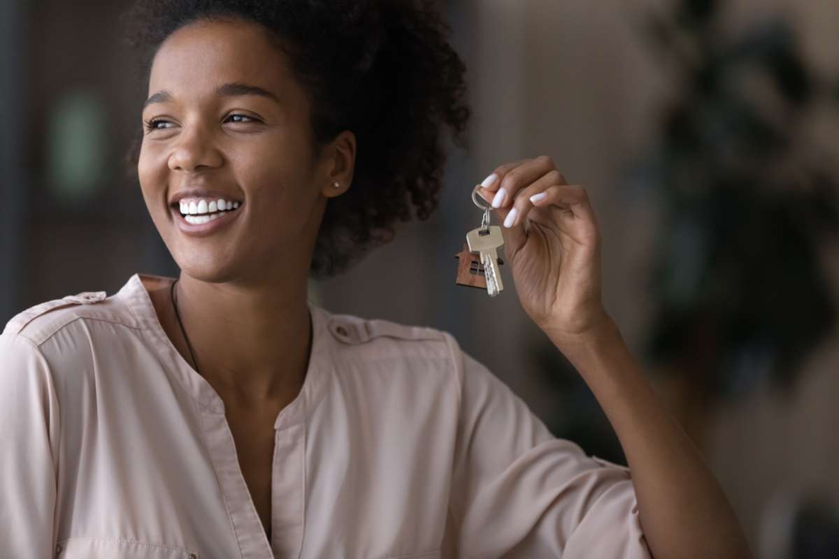 Smiling young African American woman renter or tenant hold keys to new house or apartment