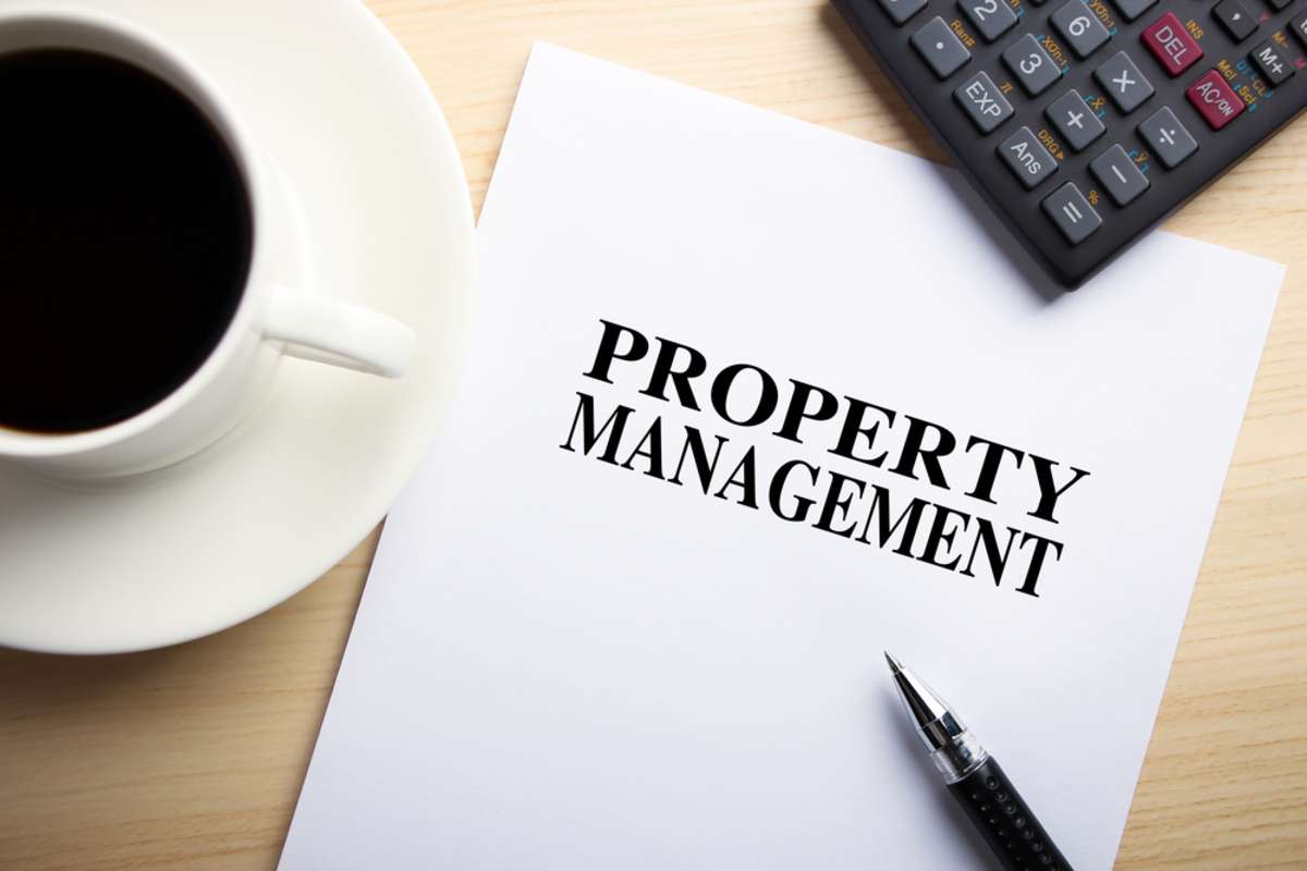 "Property Management" on white paper with coffee, calculator, and a pen, residential property management concept. 