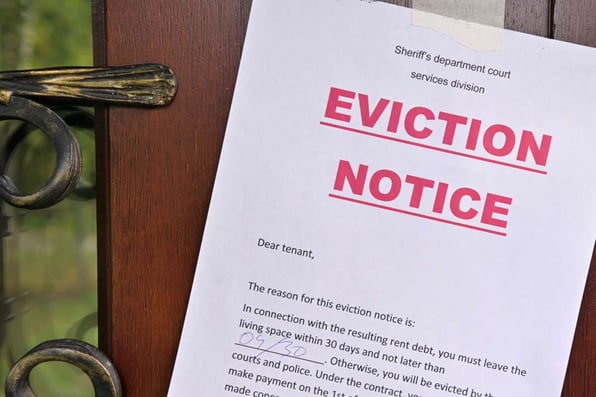 A notice of eviction of tenants hangs on the door of the house