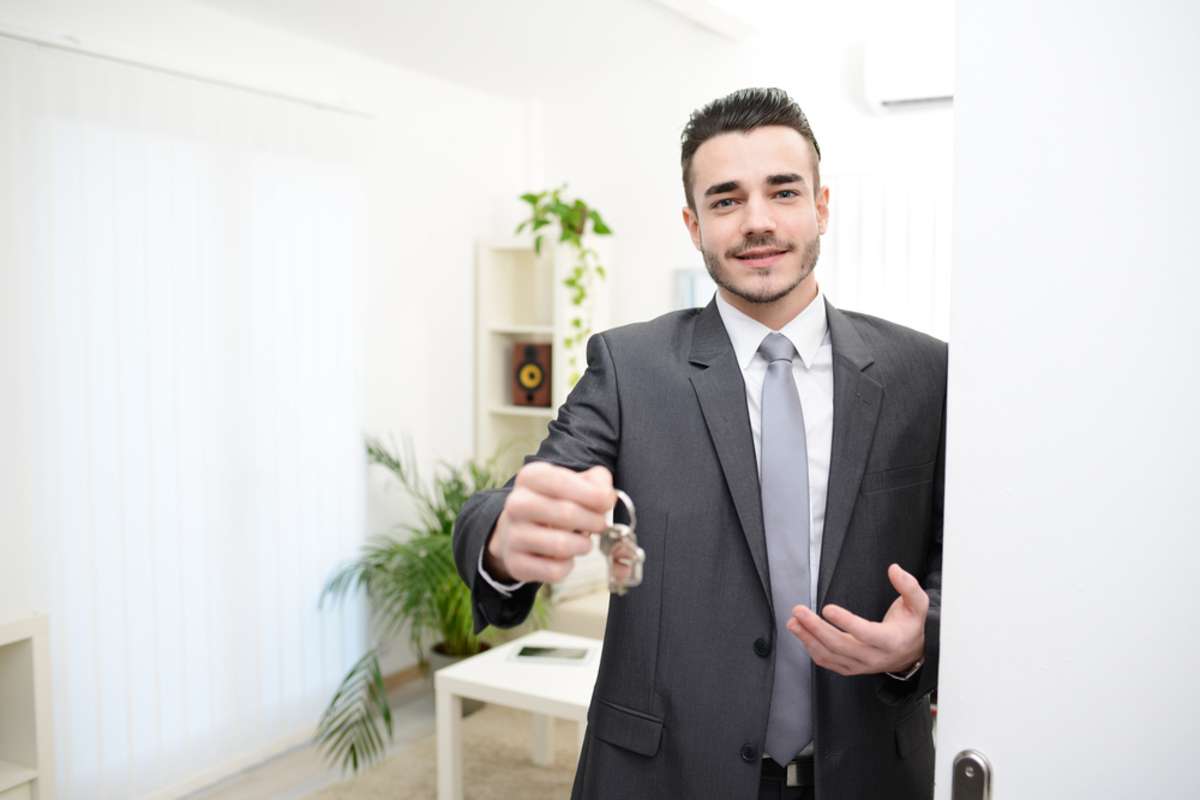 Man handing house keys in doorway of a house, Suffolk property management concept. 