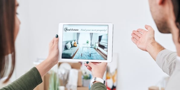 A woman holding a tablet showing a property listing.