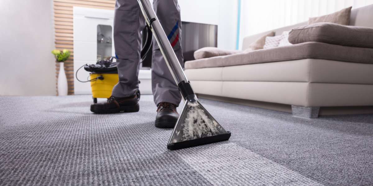 Low Section Of A Person Cleaning The Carpet With Vacuum Cleaner In Living Room