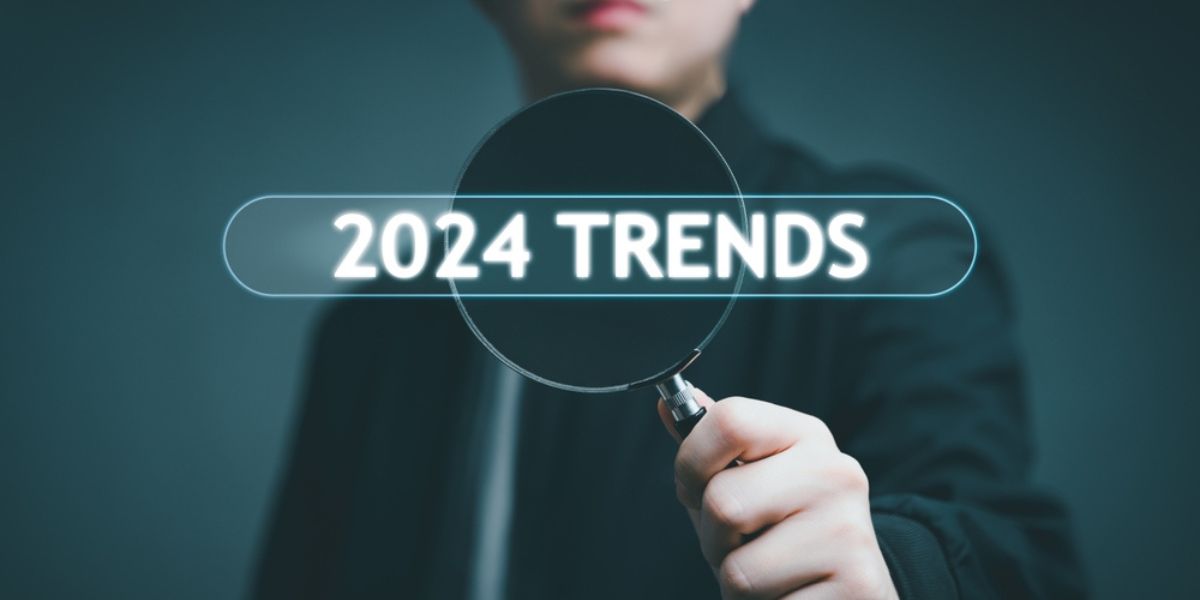 Businessman holding magnifier with 2024 Trends business, forecast new Trends
