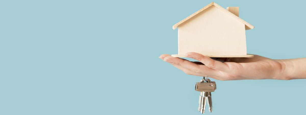 Close-up of hand holding keys and wooden house model
