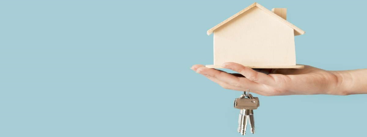 Close-up of hand holding keys and wooden house model